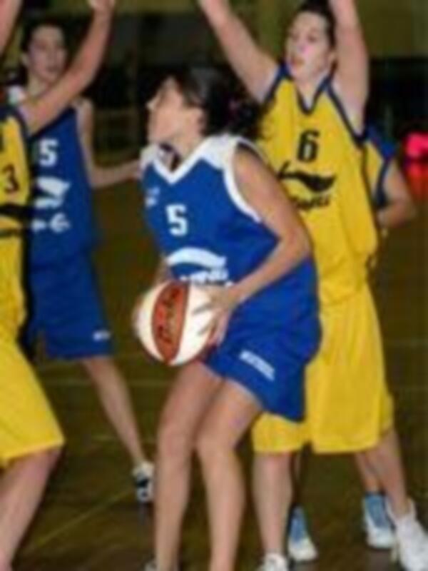 Jugadores de baloncesto en una cancha de baloncesto, con una jugadora en el centro con el número 5 en su camiseta.