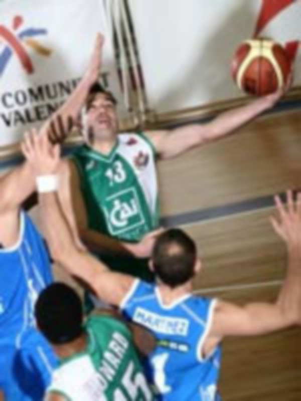 Jugadores de baloncesto en acción durante un partido. El jugador con el número 32 está bajo el control de su oponente, mientras que los demás jugadores están en posición para atacar. El fondo muestra un escudo de la Comunidad Valenciana.