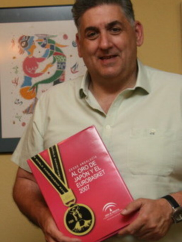 Persona sosteniendo un libro rojo con el logotipo de EuroBasket 2017 y una medalla en la portada.