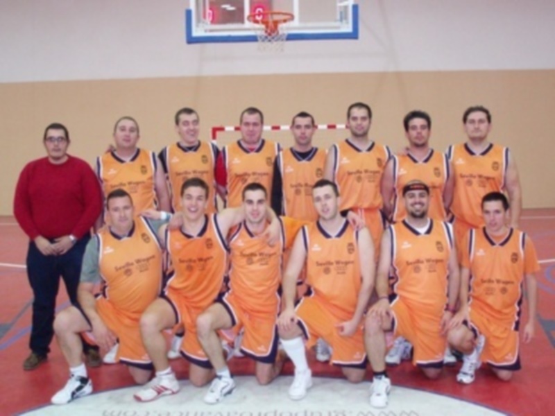 Equipo de baloncesto en uniforme naranja posando en cancha.