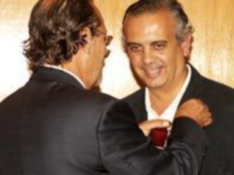 Dos hombres en trajes de negocios saludándose, uno con una corbata roja.