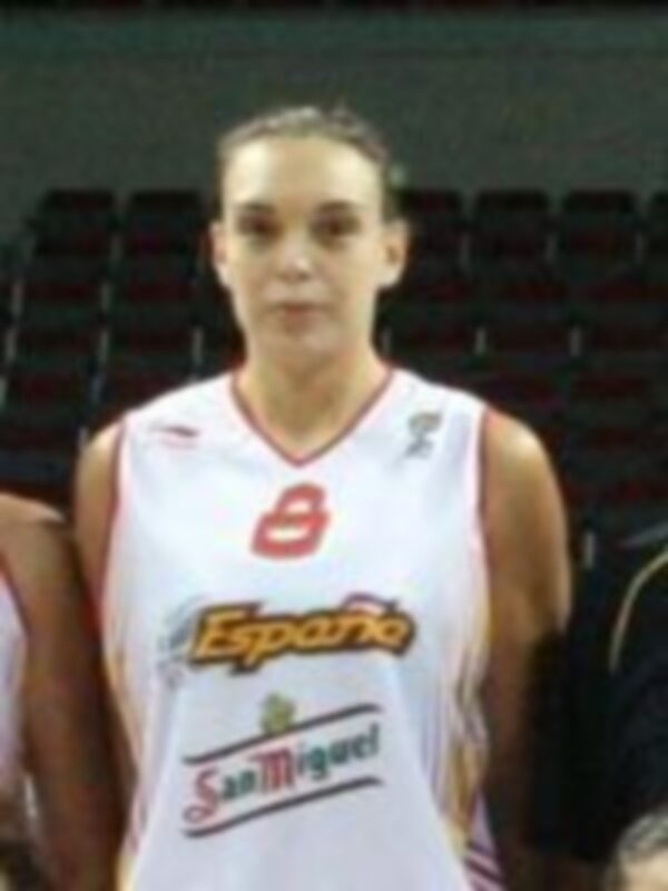 A una jugadora de baloncesto con el número 8 en su camiseta. La camiseta tiene la palabra "Español" y el logotipo de San Miguel. La jugadora está en un estadio con una grada visible al fondo, posiblemente durante un partido o entrenamiento.