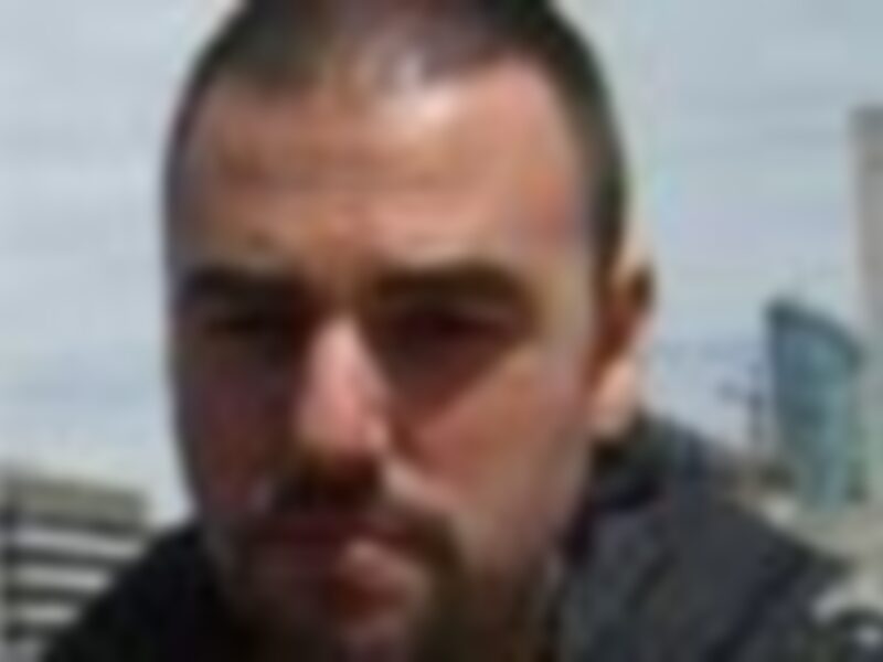 Un hombre con barba y cabello largo, mirando a la cámara.