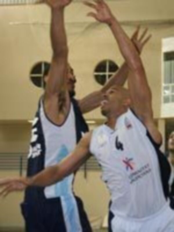 Jugadores de baloncesto en acción durante un partido, luchando por el balón bajo el aro.