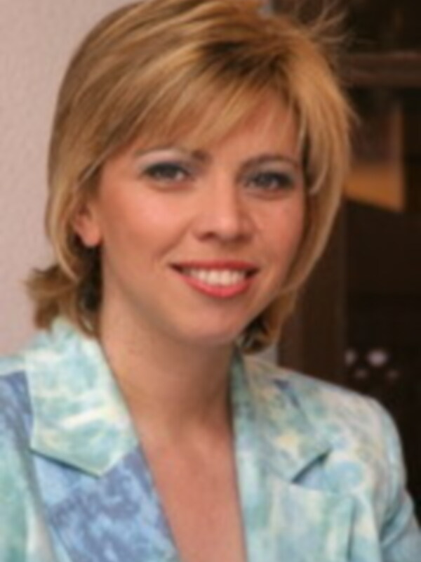 Retrato de una mujer sonriente con cabello corto y una camisa de color azul claro.