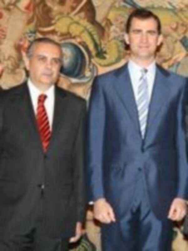 Dos hombres en trajes posan frente a un mapa del mundo, posiblemente en un contexto diplomático o político.