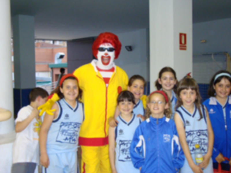 Un niño vestido con un disfraz de Ronald McDonald se encuentra entre una grupo de niños en uniformes deportivos, posando para la foto.
