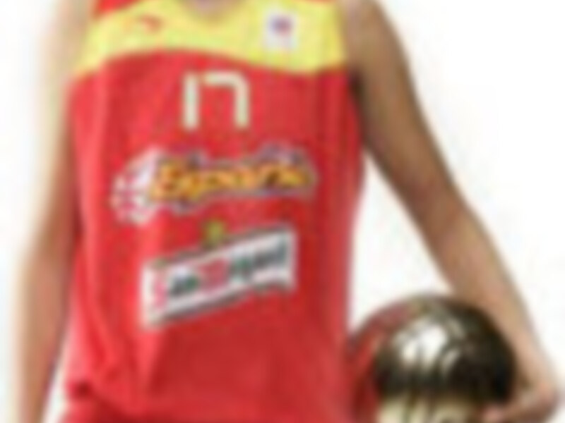 Un jugador de baloncesto en uniforme rojo y blanco con un balón bajo el brazo.