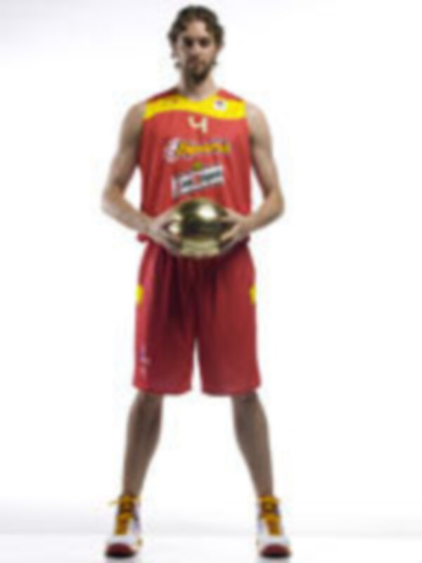 Un jugador de baloncesto con una camiseta roja y amarilla, posando con un balón de oro en la mano.