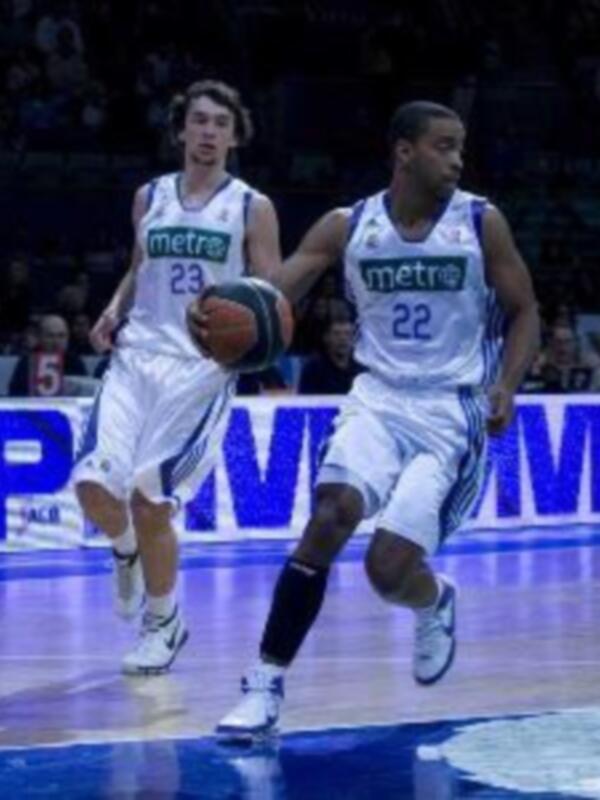 Jugadores de baloncesto en acción durante un partido, uno driblando mientras el otro lo persigue.