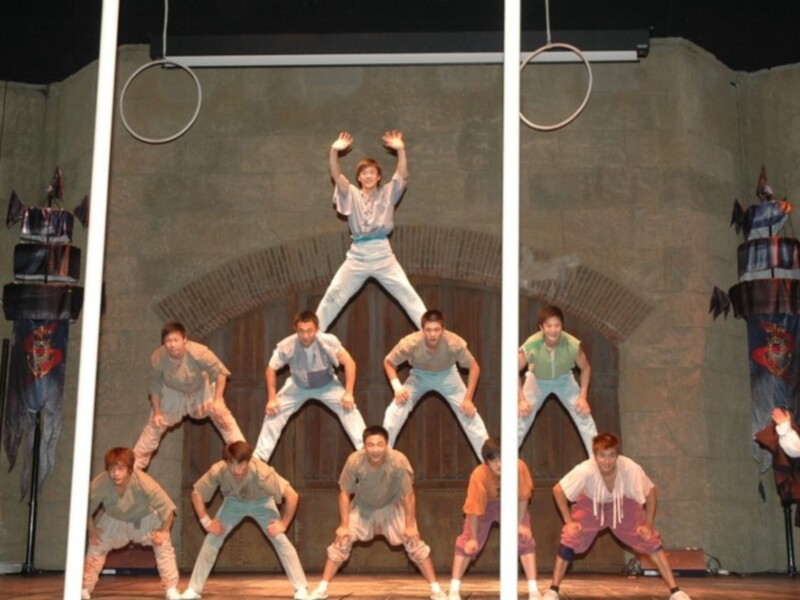 Grupo de acróbatas realizando una pirámide en el escenario de un teatro.
