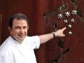 Chef pointing at a decorative wall with stars, wearing a white chef's coat.