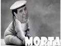 A un personaje de dibujos animados con una expresión facial sonriente y una postura erguida. El personaje lleva un traje de marinero, incluyendo una capucha y una corbata. En la imagen se puede leer el texto "MORTA" en letras grandes y blancas, lo que sugiere que este es un nombre o título relacionado con el personaje.