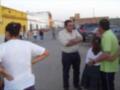 Un grupo de personas conversando en una calle, con edificios y coches al fondo.
