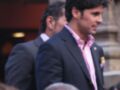 Dos hombres en trajes formales, uno con una camisa rosa y corbata amarilla, posiblemente en un evento o celebración.