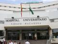 Hospital Universitario Virgen Macarena, entrada principal con banderas y personas ingresando.