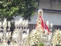 Una procesión religiosa con una imagen de la Virgen rodeada por flores y luces.