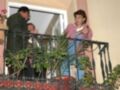 Tres personas en un balcón con plantas y una persona tomando fotos.