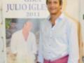 Gira Julio Iglesias 2011. Imagen de un hombre con una camisa blanca y cinturón rosa, junto a una portada de revista con su nombre.
