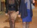 Dos mujeres caminando por una calle nocturna, una con falda leopardo y la otra con vestido azul y bufanda estampada.