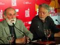 Dos hombres en una conferencia de prensa, uno con barba blanca y el otro con barba gris. Detrás de ellos hay un cartel del Festival de Cine Europeo Sevilla 2019.