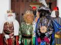 Tres personajes vestidos como los Reyes Magos, con trajes elaborados y sombreros decorativos.