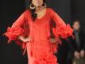 Model wearing a vibrant red flamenco dress with intricate details and a matching headpiece.
