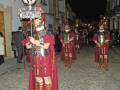 Recreación histórica de soldados romanos en una procesión nocturna en una calle adoquinada.