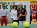 Los jugadores ganadores de un torneo de tenis posan con sus trofeos y pelotas en una cancha de tenis.