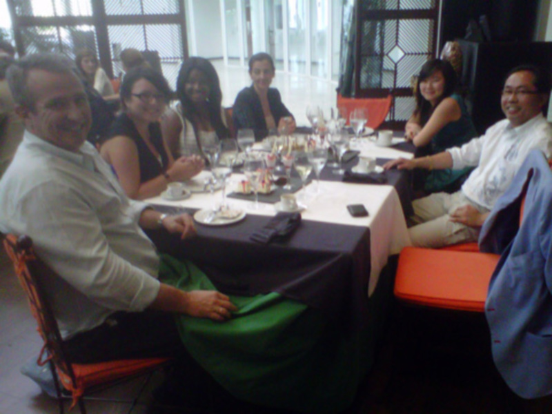 Una reunión en una sala con mesas cubiertas, gente sentada y conversando.