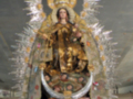 Imagen de una Virgen María en un altar con ornamentos dorados y cristales.