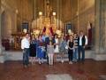 Fotografía familiar en una iglesia con un altar y vitrales. Todos los miembros de la familia están vestidos formalmente, posando juntos en el centro del salón. La imagen transmite un sentimiento de unidad y felicidad familiar en un ambiente religioso.