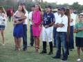 Grupo de personas observando un evento en un campo de polo, con ropa deportiva y casual.