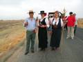 Personas con trajes tradicionales y botellas de cerveza en un camino rural.