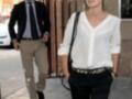 Dos personas caminan por una calle, uno con traje y corbata, la otra con blusa blanca y pantalones negros. Detalle de una campana en la imagen.