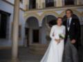 Una pareja se encuentra en el patio de un edificio histórico, posando para la foto. La mujer lleva un vestido blanco largo y el hombre está vestido con traje negro.