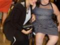 Dos mujeres sonríen y bromean en un evento, una está sentada en una silla de ruedas.