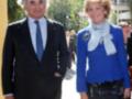 Dos personas posan juntas en un evento formal, uno con traje y corbata azul, la otra con chaqueta azul y falda negra.