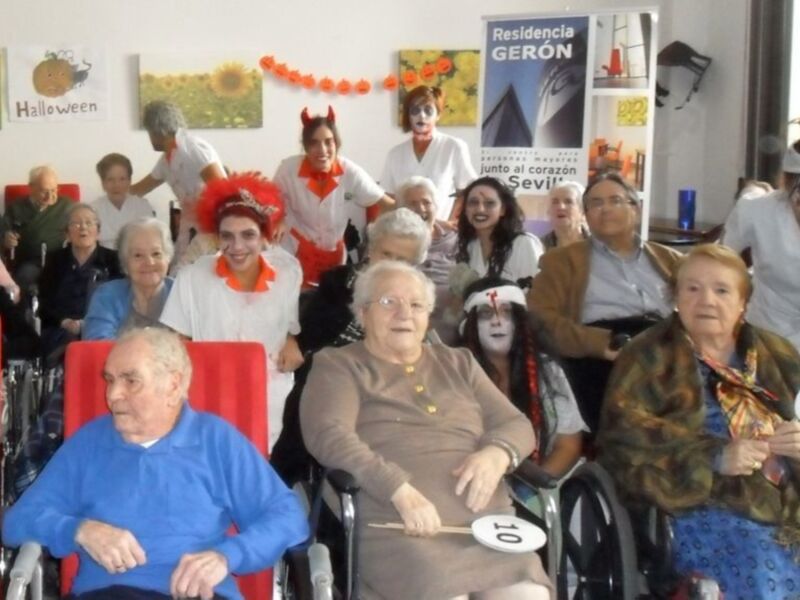 Celebración de Halloween en una residencia de mayores con participantes disfrazados y felices.