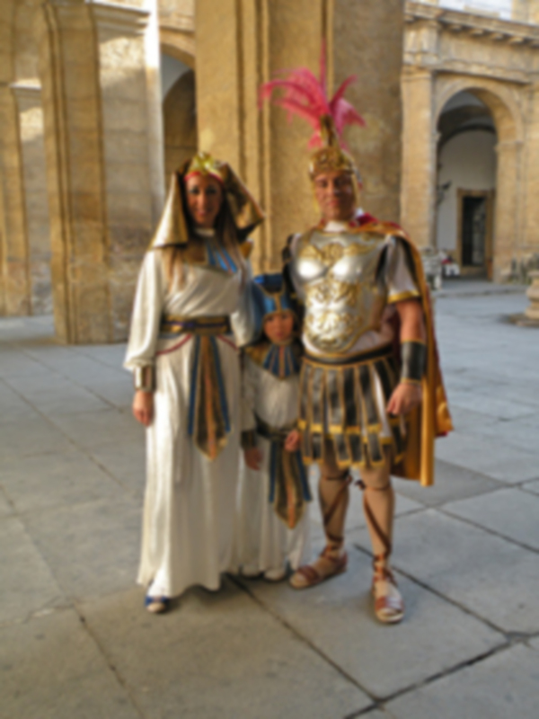 Personajes disfrazados de Egipto y Roma en un patio histórico.