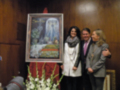 Presentación de un lienzo de la Virgen de la Caridad en Sevilla, con tres personas posando junto a él.