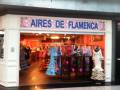 Tienda de ropa flamenca con vestidos y falda en el escaparate.