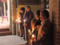 Una imagen de una iglesia con personas rezando en silencio, rodeadas de velas encendidas que iluminan el ambiente. La atmósfera es tranquila y reverente, destacando la importancia de la oración en este lugar sagrado.