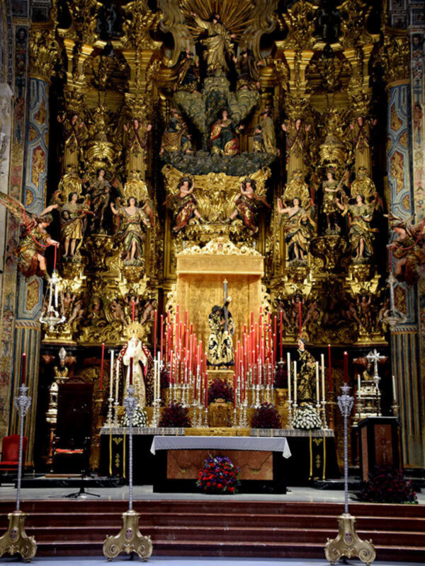 Altar barroco ornado con figuras doradas y altares laterales en una iglesia.