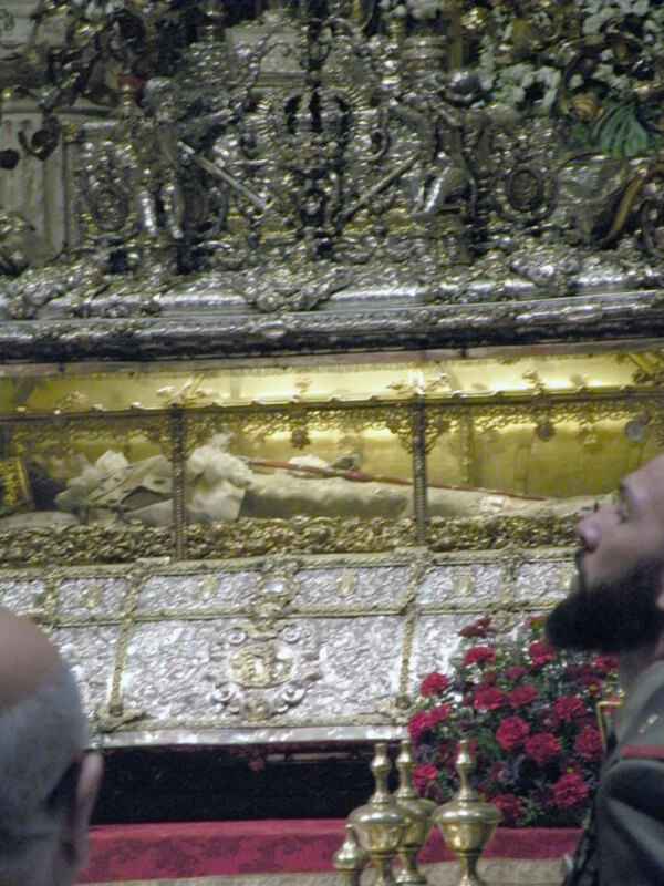Detalles de un altar con figuras religiosas y flores en el fondo.