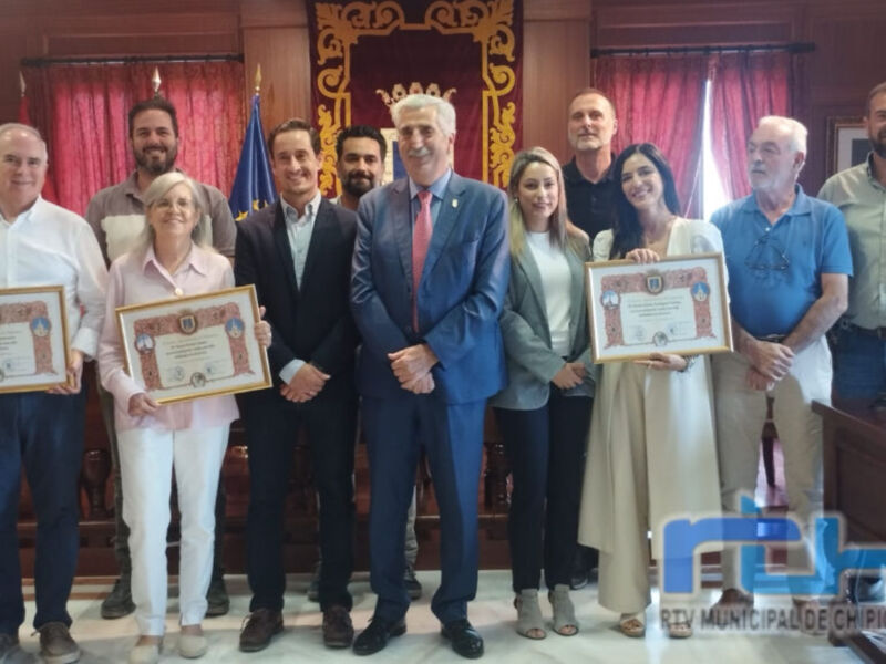 Una imagen de un grupo de personas en una sala de conferencias, posando con diplomas. El ambiente es formal y el grupo está celebrando un reconocimiento o premio.