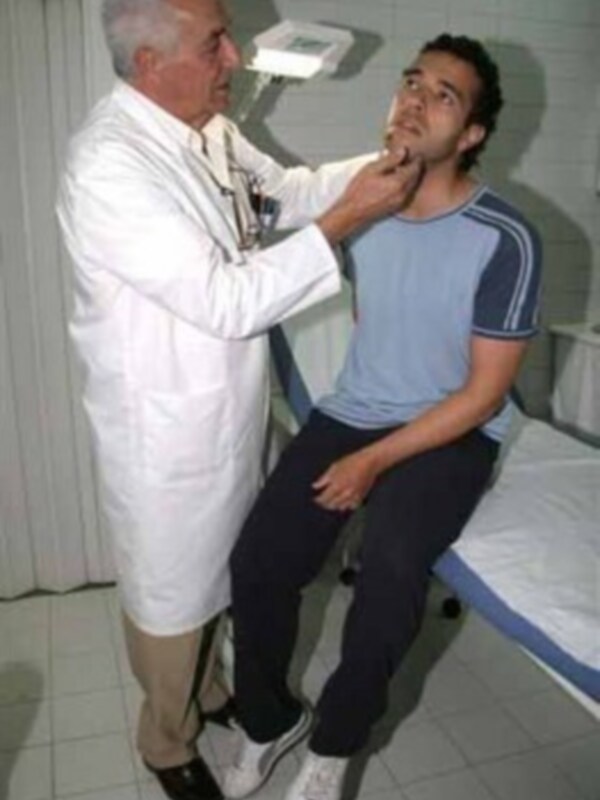 Un médico examina la garganta de un paciente en una consulta médica.