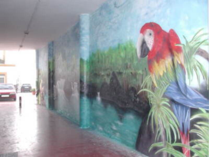 Mural de un loro en un muro de una calle.