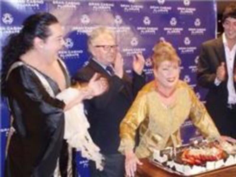 Un grupo de personas en una celebración, con una mujer en el centro que sostiene una taza. La imagen parece ser de una celebración formal, posiblemente un evento empresarial o deportivo.