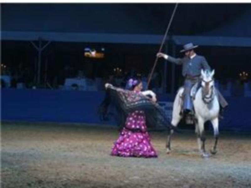 Actores en trajes típicos de España, una bailaora y un caballero, en un escenario de torneo de equitación.